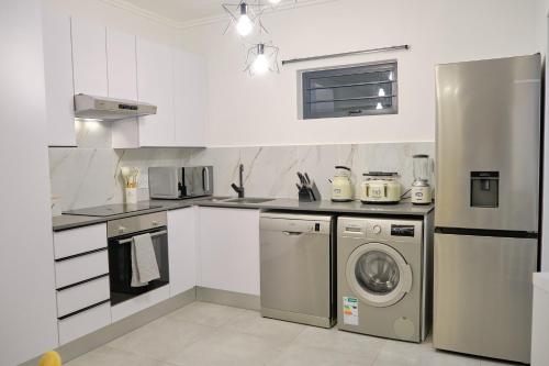 a kitchen with a refrigerator and a washer and dryer at Medon Luxury Suites with power back up Bryanston Sandton in Johannesburg