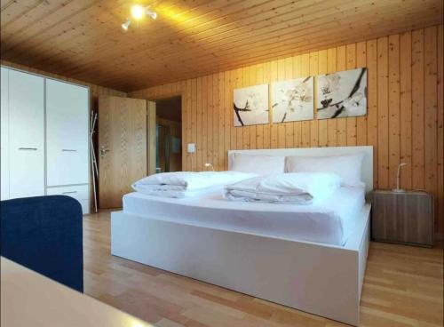 a large white bed in a room with wooden walls at Swiss Apartment Thunersee in Einigen