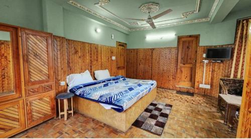 1 dormitorio con 1 cama y TV en Hotel Jubilant Manali, en Manali