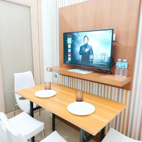 una camera con televisore e tavolo con sedie di Sea Residences by Jan & Val Alano a Manila