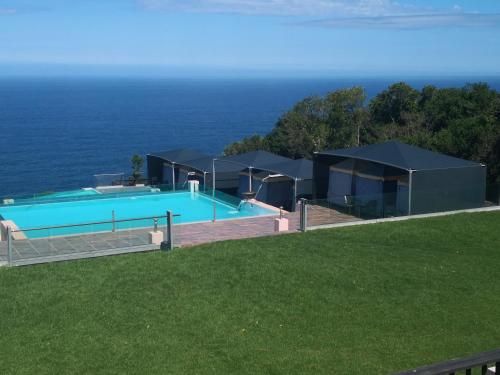a house with a swimming pool next to the ocean at Tsitsikamma on Sea Poolside Cabanas - they are not tents in Witelsbos
