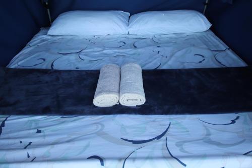 ein Bett mit zwei Kissen und zwei Handtüchern darauf in der Unterkunft Tsitsikamma on Sea Poolside Cabanas - they are not tents in Witelsbos
