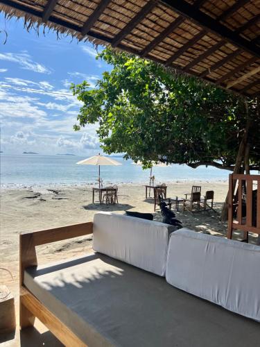 Ursula Beach Resort في إل نيدو: أريكة على شاطئ به طاولة ومظلة