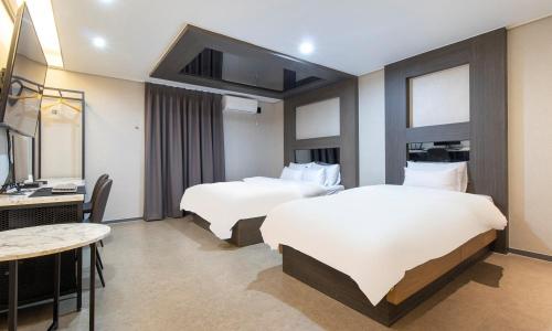 a hotel room with two beds and a desk and a television at Hwaseong Stay13 Hotel in Hwaseong