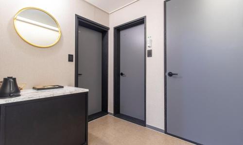 a bathroom with two doors and a mirror on the wall at Hwaseong Stay13 Hotel in Hwaseong