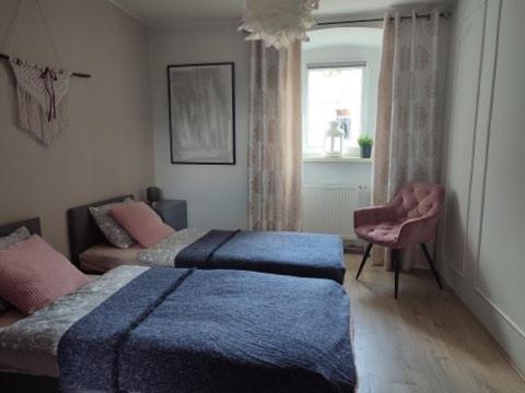 een slaapkamer met 2 bedden, een stoel en een raam bij Apartament 44 in Lądek-Zdrój