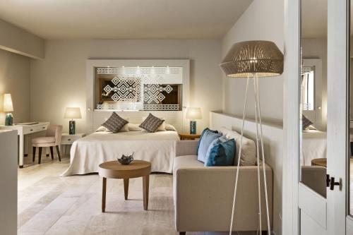 a bedroom with a bed and a couch and a table at Hotel La Bisaccia in Baja Sardinia