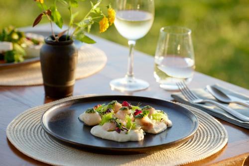 einen Teller mit Essen auf einem Tisch mit Gläsern Wein in der Unterkunft Ikos Odisia in Korfu-Stadt