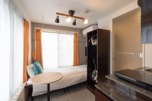 Schlafzimmer mit einem Bett, einem Tisch und einem Fenster in der Unterkunft HJ PLACE SHIBUYA in Tokio