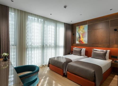 a bedroom with two beds and a chair at Nex Hotel Istanbul City Center in Istanbul