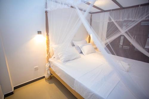 Habaraduwa Central的住宿－Kusumvillahabarduwa，卧室配有带蚊帐的白色床