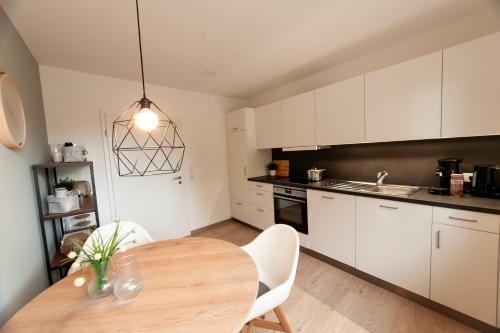 cocina con mesa de madera y armarios blancos en FreiTraum Apartments No1 im Zentrum von Bad Neustadt en Bad Neustadt an der Saale