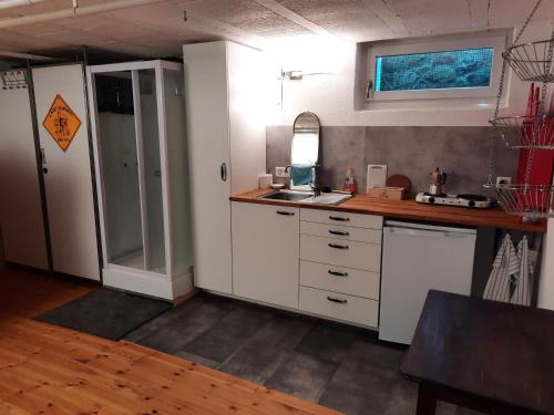 una cocina con armarios blancos y fregadero en grosses Zimmer mit Küche/Du/WC zur Alleinnutzung, en Kappel am Albis