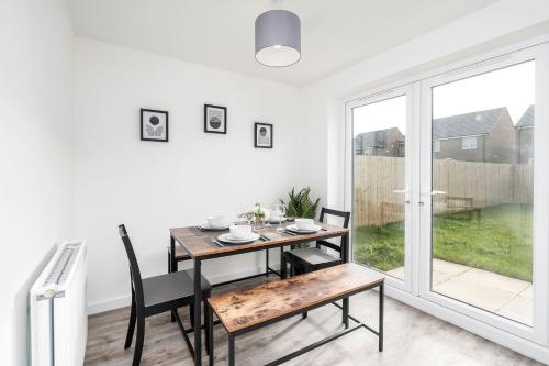 a dining room with a table and chairs and a window at Modern, Stylish House with Free Parking and Garden in Humberston