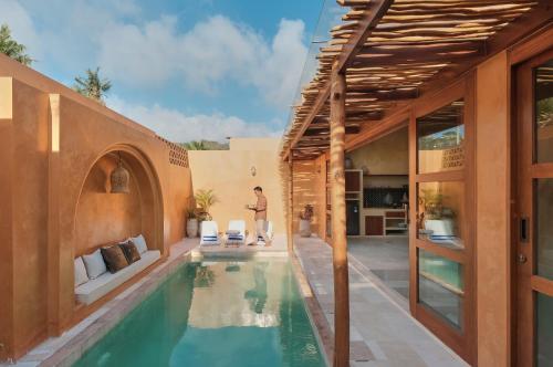 a pool in a house with a person standing next to it at Lina Boutique Villas and Spa in Kuta Lombok