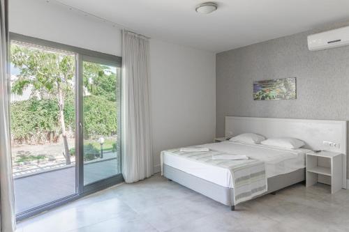a white bedroom with a bed and a large window at ZEF RESIDENCE in Bodrum City