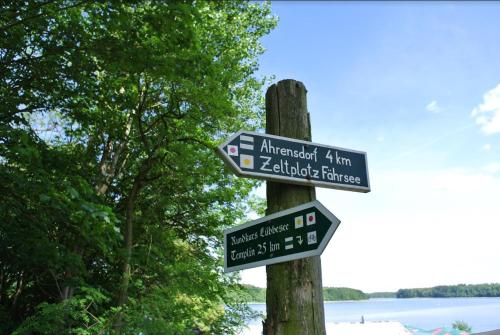 a pole with street signs on it next to a lake at Elf am See - Haus 10 in Templin
