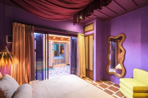 チャングーにあるEl Barrio Boutique Hotel & Barの紫色のベッドルーム(ベッド1台、黄色の椅子付)