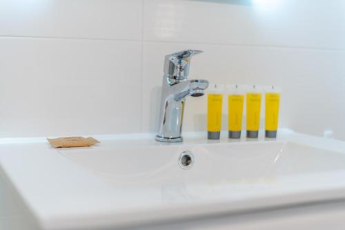 ein Waschbecken mit Wasserhahn und einigen gelben Gläsern in der Unterkunft Osiedle Kombatantów Standard Apartment in Krakau
