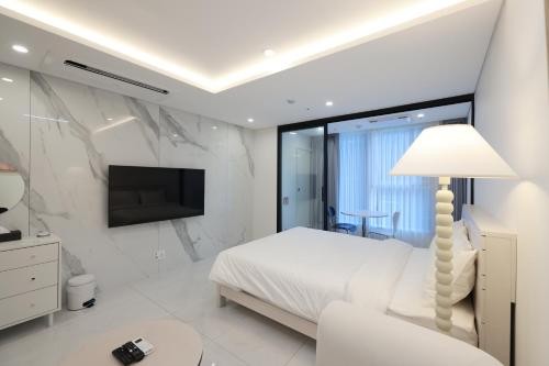 biała sypialnia z łóżkiem i telewizorem w obiekcie Zizel Raonjae 2 w Seulu