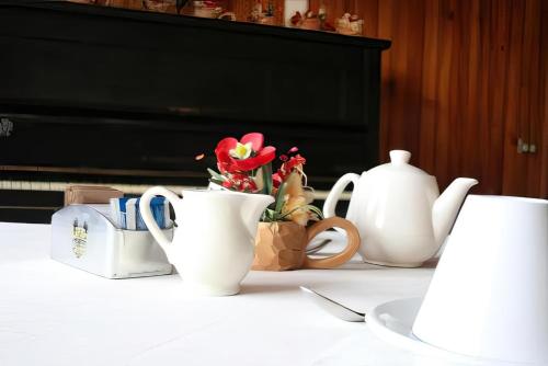 ヴァルディソットにあるHotel Ristorante San Pietroの白いカップと花瓶とピアノが並ぶテーブル