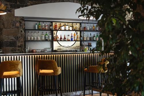 a bar with two bar stools and a shelf with alcohol at Hotel Montbrillant in Geneva