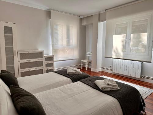 1 dormitorio con 2 camas y 2 ventanas en Apartxibi, en Bermeo