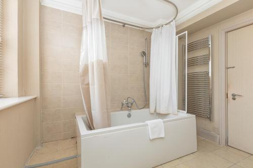 a white bathroom with a tub and a shower at Exceptional 3BDR flat in Mayfair in London