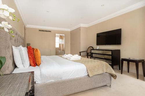 a bedroom with a large white bed and a flat screen tv at Exceptional 3BDR flat in Mayfair in London