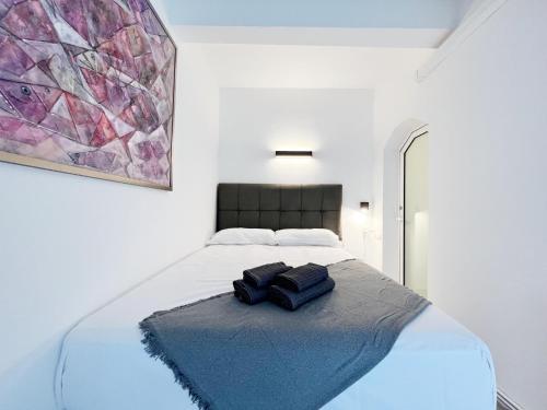 een witte slaapkamer met een bed met twee zwarte voorwerpen erop bij Cosy Montroig Sitges in Sitges