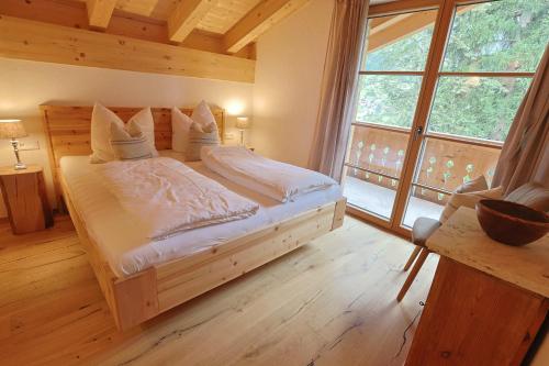 a bedroom with a wooden bed with a large window at Haus Bödmenstein in Tschagguns