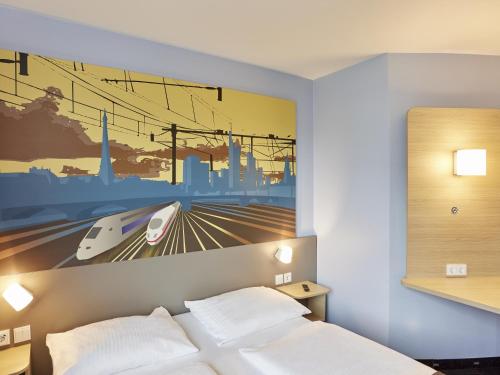 a bedroom with a poster of a train at B&B Hotel Saarbrücken-Hbf in Saarbrücken