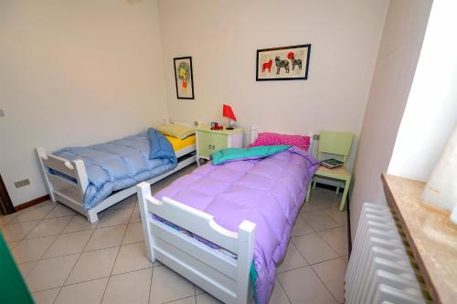 two beds in a room with purple and blue sheets at Orsini: tre camere da letto, 2 bagni in Luco dei Marsi