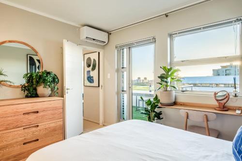 a bedroom with a bed and a window with plants at The Apartment in Mouille Point in Cape Town