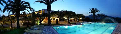 a swimming pool with palm trees and a building at Paradise Hotel Corfu in Gouvia