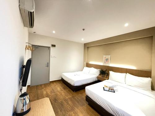 Cette chambre comprend deux lits et une télévision. dans l'établissement Swing & Pillows - KL Sri Petaling, à Kuala Lumpur