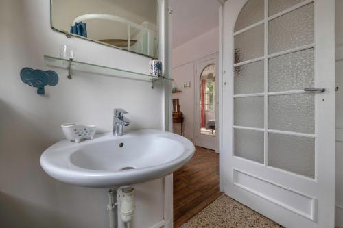 La salle de bains est pourvue d'un lavabo blanc et d'un miroir. dans l'établissement Escapade conviviale et familiale pres de la plage, à Pornichet