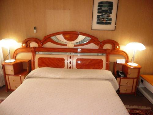 a bedroom with a wooden bed with two night stands at Hôtel Source Du Nil in Bujumbura