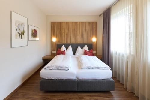 a bedroom with a large white bed with red pillows at Hotel Staffler in Odelzhausen