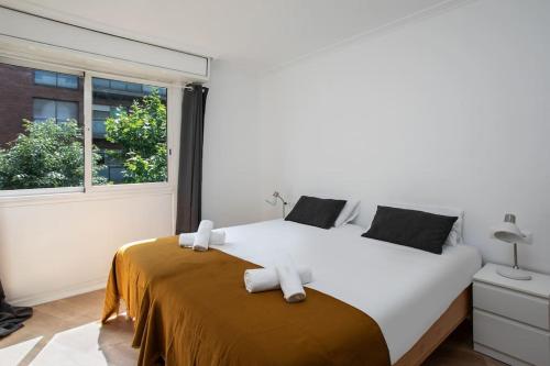 um quarto com uma grande cama branca e uma janela em Canela Homes BARCELONA PADILLA em Barcelona