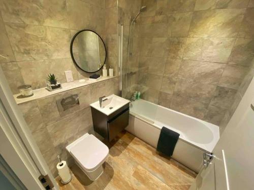 a bathroom with a tub and a toilet and a sink at Beautiful 1 Bed Flat near NEC with secure parking in Birmingham