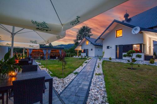 Cette maison dispose d'une terrasse avec une table et un parasol. dans l'établissement Willa Rynek - pokoje i domki, à Tylicz