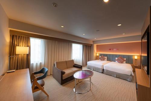 広島市にあるザ ロイヤルパークホテル 広島 リバーサイドのベッド、ソファ、椅子が備わるホテルルームです。