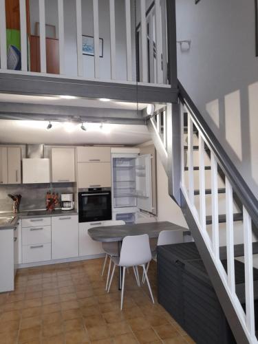 une cuisine avec des placards blancs, une table et un escalier dans l'établissement La grande bleue, à Port-Leucate