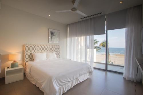 a bedroom with a bed and a view of the beach at Faru Beachfront Villa Sanctuary Ho Tram in Ho Tram