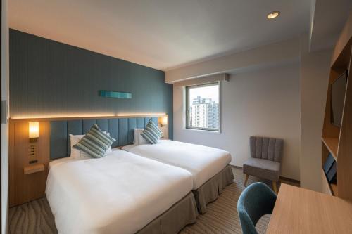 a hotel room with a large bed and a chair at The Royal Park Hotel Hiroshima Riverside in Hiroshima