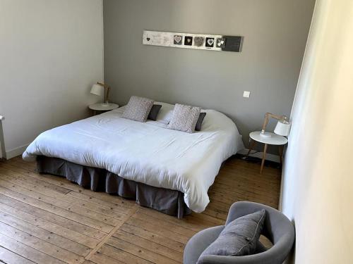 ein Schlafzimmer mit einem weißen Bett und einem Stuhl in der Unterkunft Superbe gîte pour 15 personnes in Le Ménil-Brout