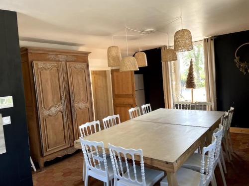 comedor con mesa de madera y sillas blancas en Superbe gîte pour 15 personnes, en Le Ménil-Brout