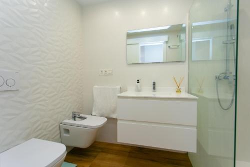 a bathroom with a toilet and a sink and a mirror at Cullera Beach Apartment Espacio in Cullera
