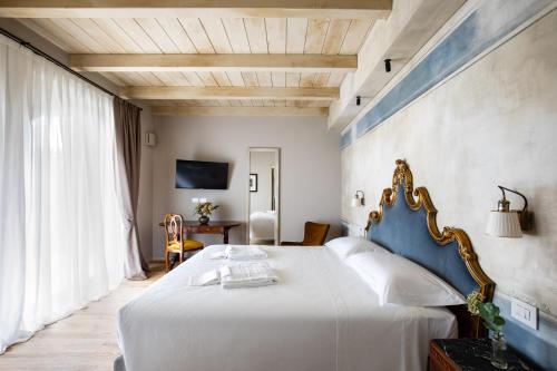 a bedroom with a large white bed with a blue headboard at Country House Oliveto sul Lago in San Nicolò
